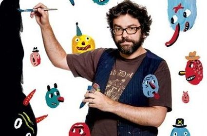 Author Liniers poses with a paint brush and several of his characters floating around him