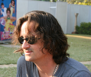 Author Jeff Smith poses for the camera outside in sunglasses and a blue shirt
